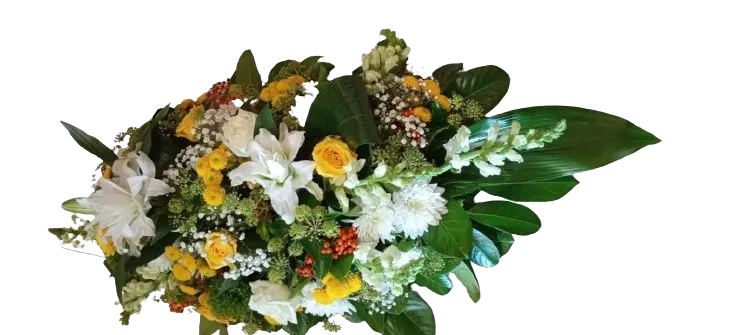 Coussin de fleurs de deuil allongé composé de lys blancs, roses et fleurs jaunes.