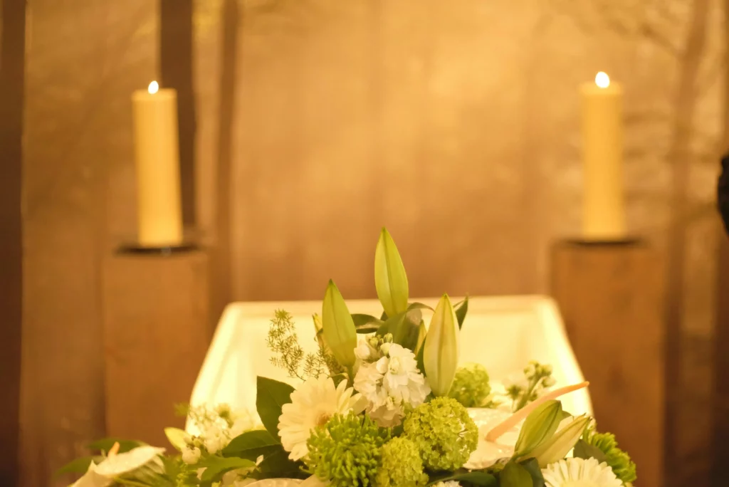 Composition de fleurs blanches et bougies près d'un cercueil en cérémonie.